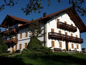 A multi-story building with balconies, a tree in front, and a clear blue sky. - Mayrhof - Mountain View (Eggstatt)