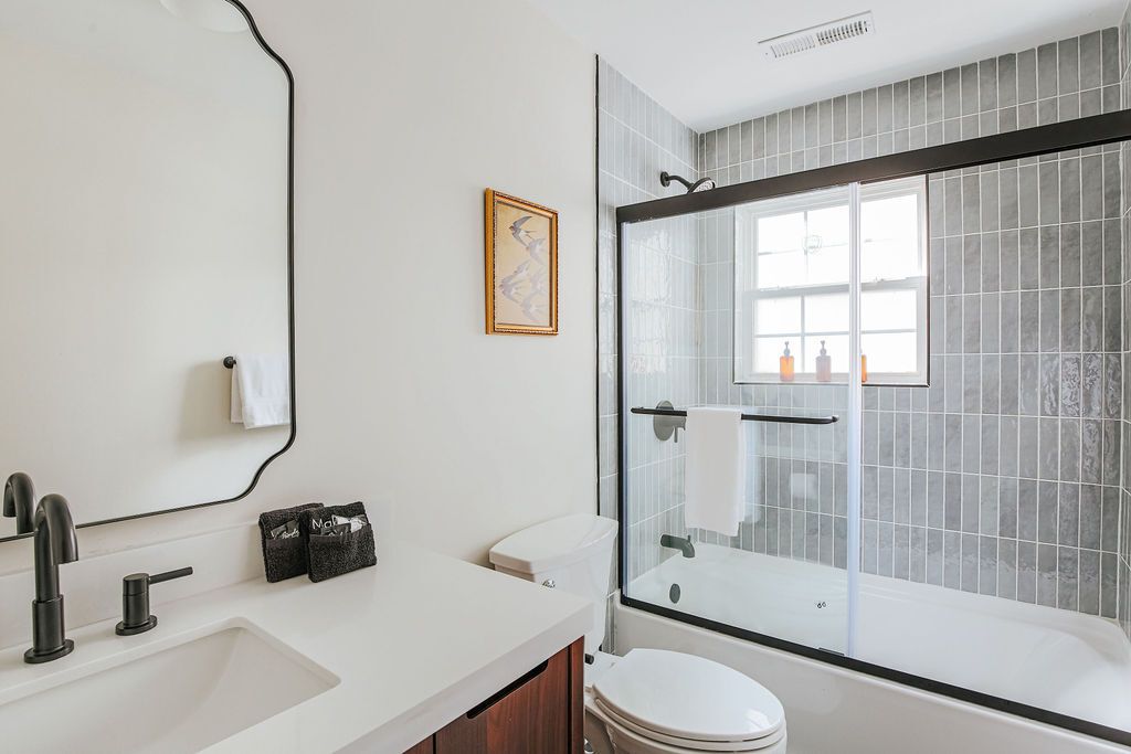 Een moderne badkamer met een wit wastafelmeubel, een zwarte kraan en een douchecabine met glazen wanden.