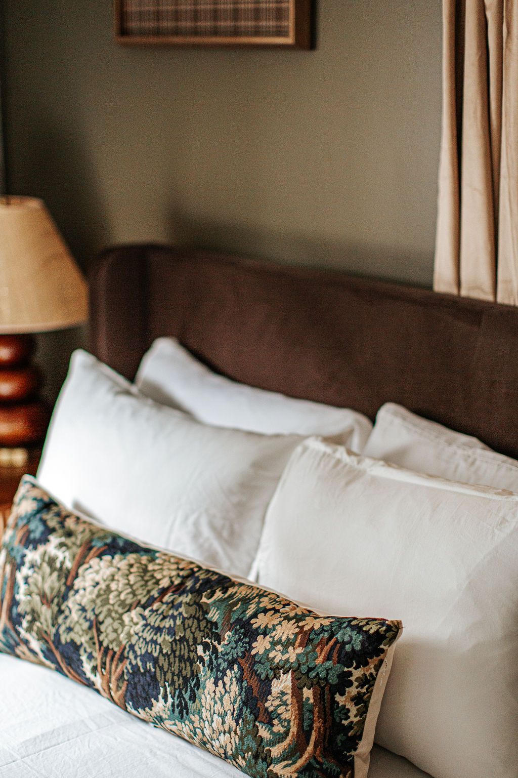 A bed with white pillows and a patterned throw pillow.