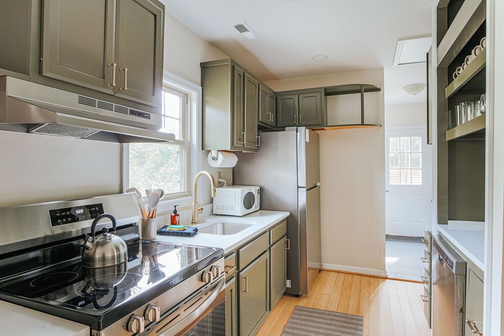 Una cocina equipada con estufa, microondas, refrigerador y armarios.