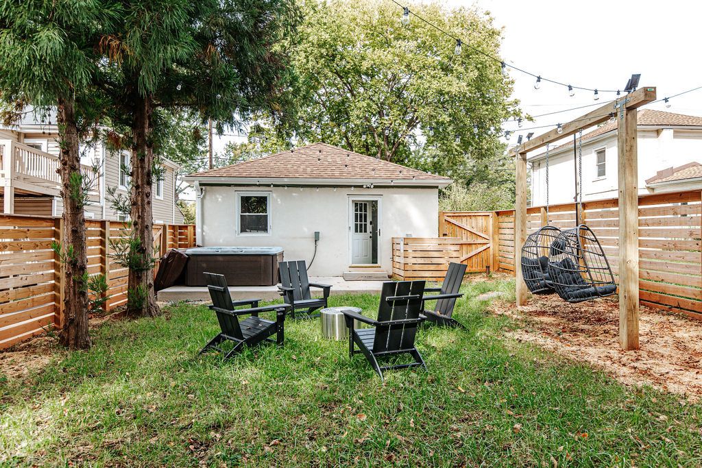 Un jardin avec un espace patio, des sièges d’extérieur et une balançoire.