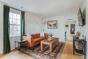 Una sala de estar con un sofá de cuero, una mesa de centro de madera y un televisor montado en la pared.