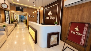 Zona d'acollida amb taulell de recepció, un rellotge i un senyal per Vee Stay.