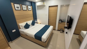 Una habitación de hotel moderna con cama, mesita de noche y televisor montado en la pared.