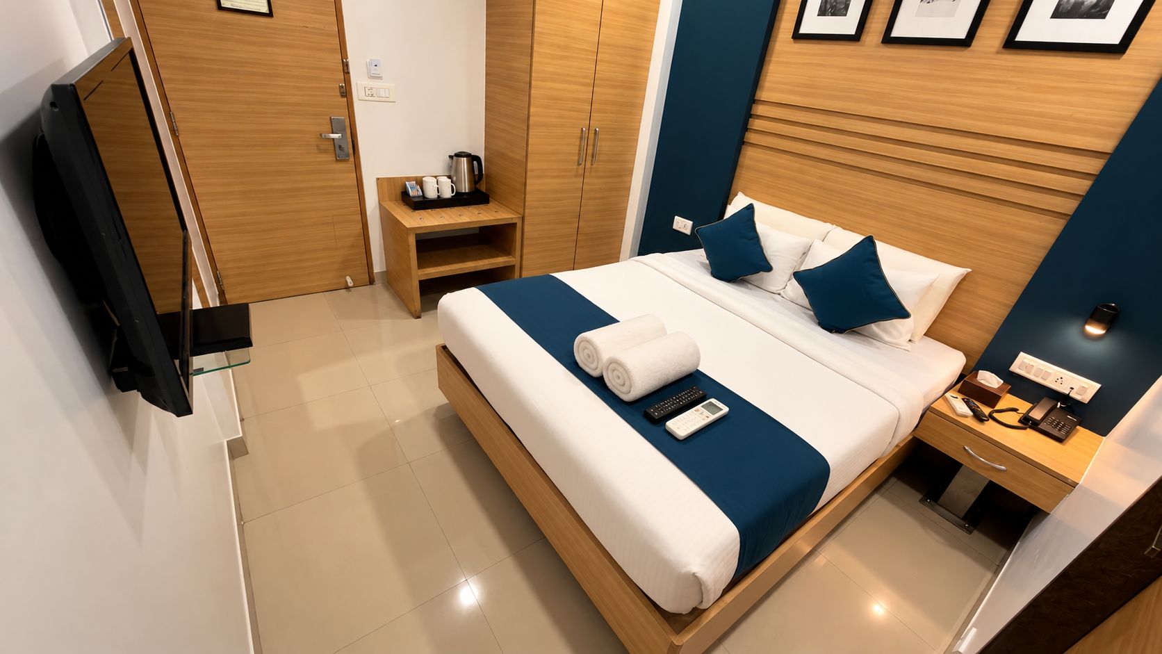 Una habitación de hotel con una cama, mesita de noche y televisor.
