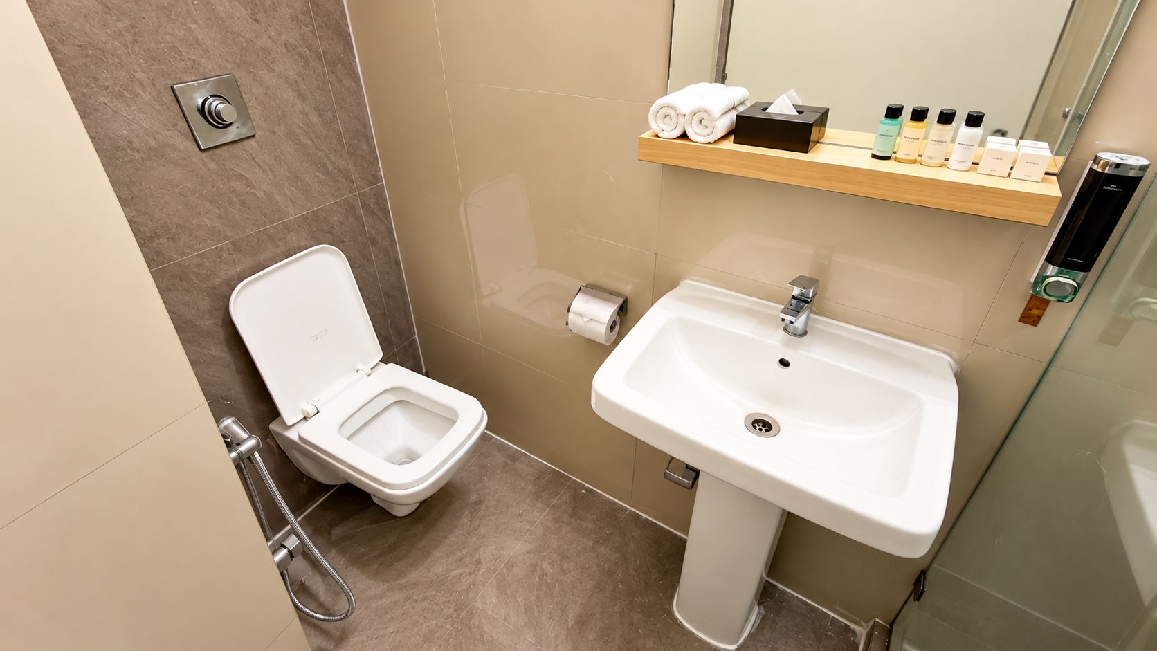 Un baño moderno con inodoro, lavamanos y estante con artículos de tocador.