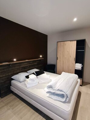 Ein modernes Hotelzimmer mit einem großen Bett, einem Holzschrank und einem Nachttisch mit einer Lampe.