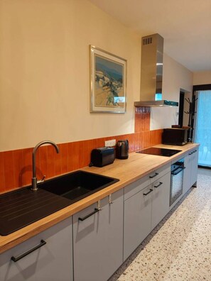 Een moderne keuken met twee spoelbakken, een broodrooster en een waterkoker op het aanrecht.