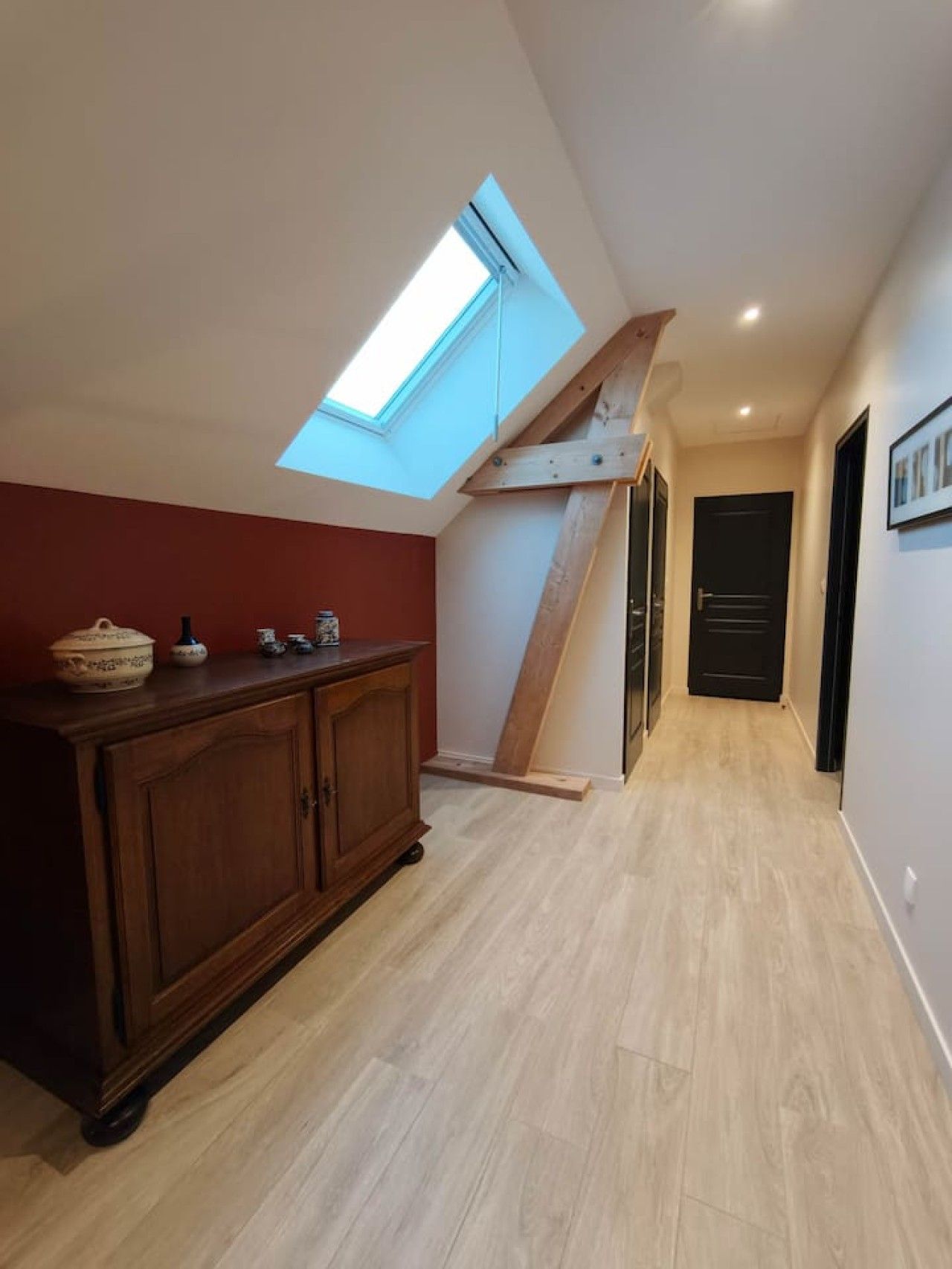 Un couloir doté d’une lucarne, d’un plancher en bois et d’une armoire en bois foncé.