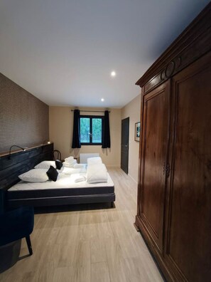 Een hotelkamer met een bed, een kledingkast, een raam met gordijnen en een wand met een structuur.