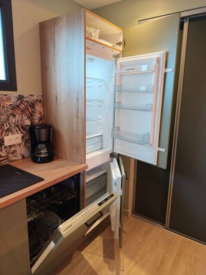 Cocina compacta con lavavajillas integrado, cafetera y refrigerador con múltiples estantes.