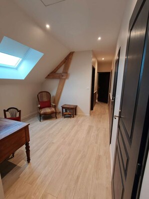 Una habitación con techo inclinado, un tragaluz, una mesa de comedor, una silla y una mesita.