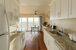 A kitchen with a view of the ocean, a dining area with chairs, and a ceiling fan. - Ocean Haven | Beachfront Getaway by Redondo Pier (Redondo Beach)