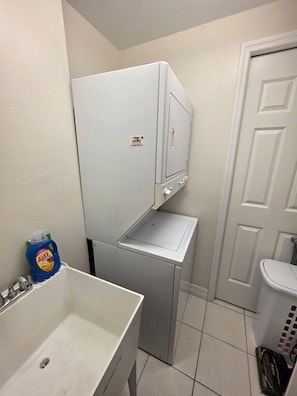 Bany petit i funcional amb un lavabo blanc, una petita superfície de treball i un vàter blanc, a més d'una porta blanca.