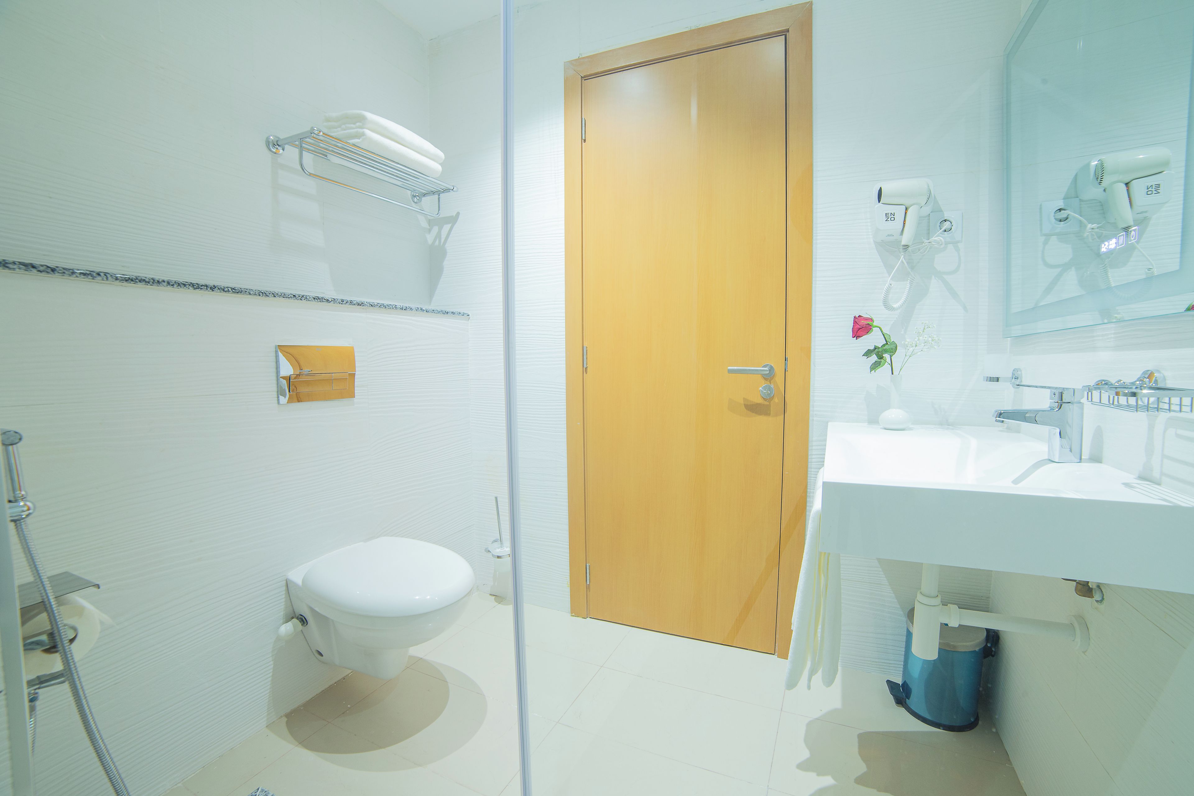 Un baño con inodoro, lavamanos, espejo, secador de pelo y ducha.