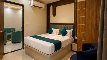 Un dormitorio moderno con una cama, ventilador de techo, armario y un rincón de descanso con una silla.