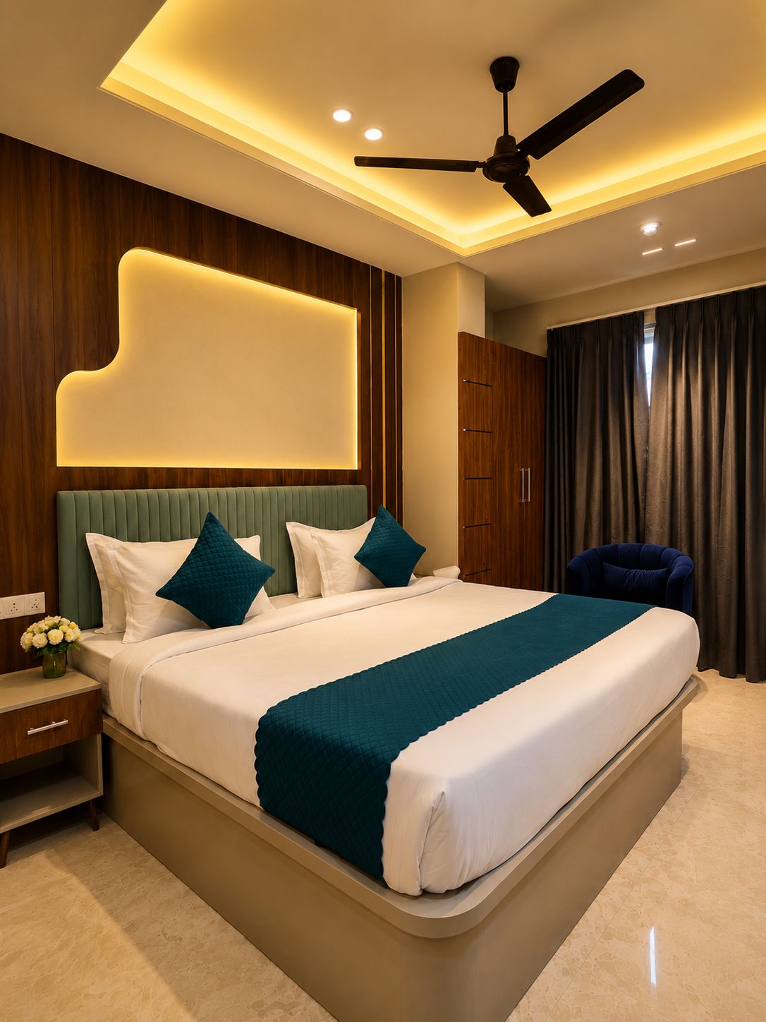 A modern hotel room with a large bed, a ceiling fan, and a nightstand with a vase of flowers.
