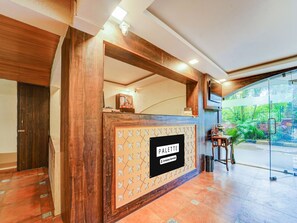 A reception desk with a sign reading 'PALETTE Company-Serviced' and a view of a lush garden through a glass door. - Classic Aveeno Villas (Saligao)