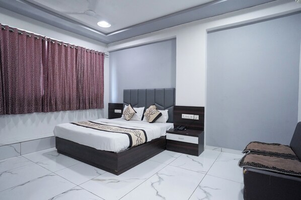 A modern bedroom with a large bed, a bedside table, a nightstand, and a chair.