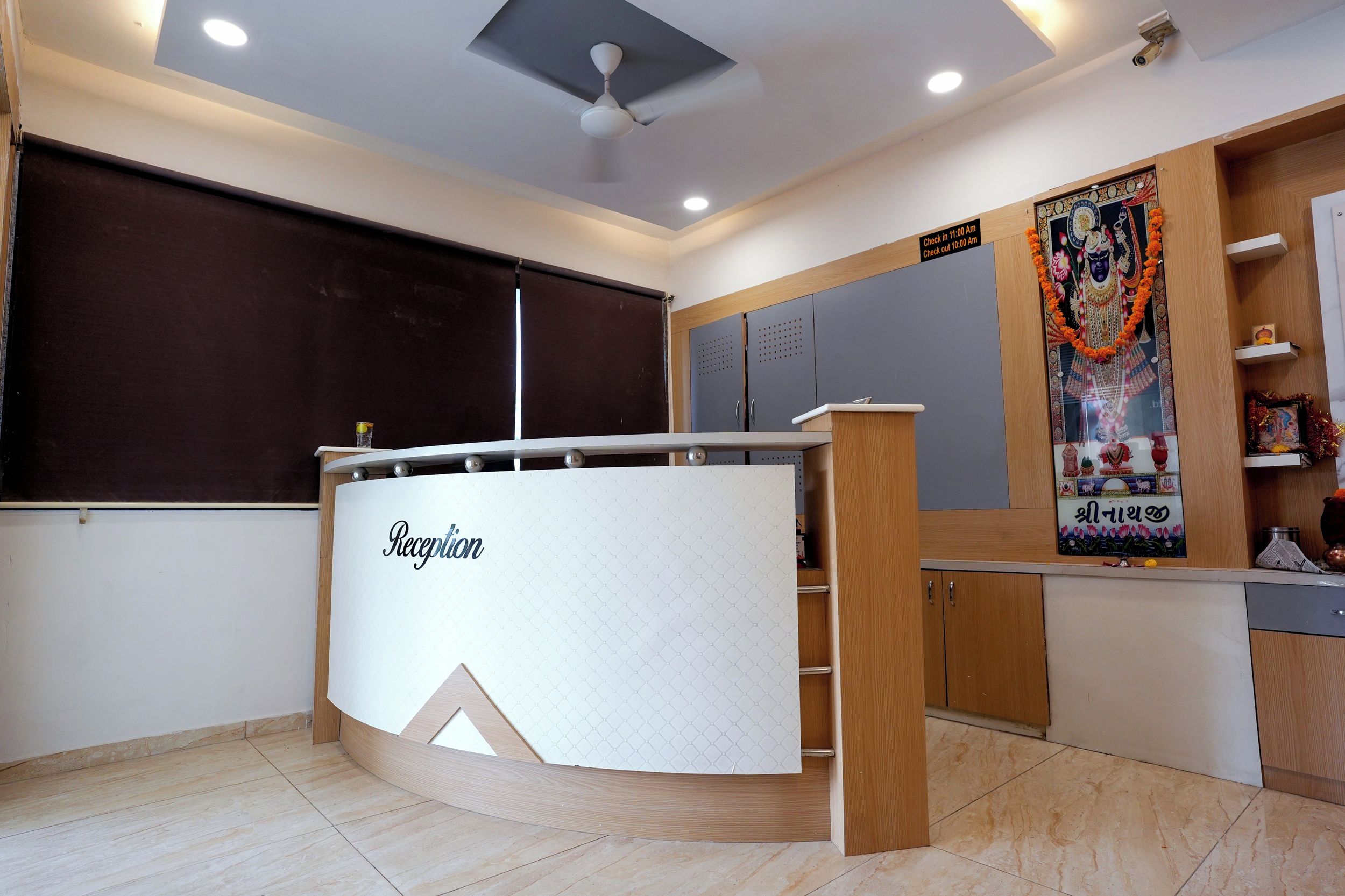A reception area with a reception desk, a ceiling fan, and a wall with a poster.