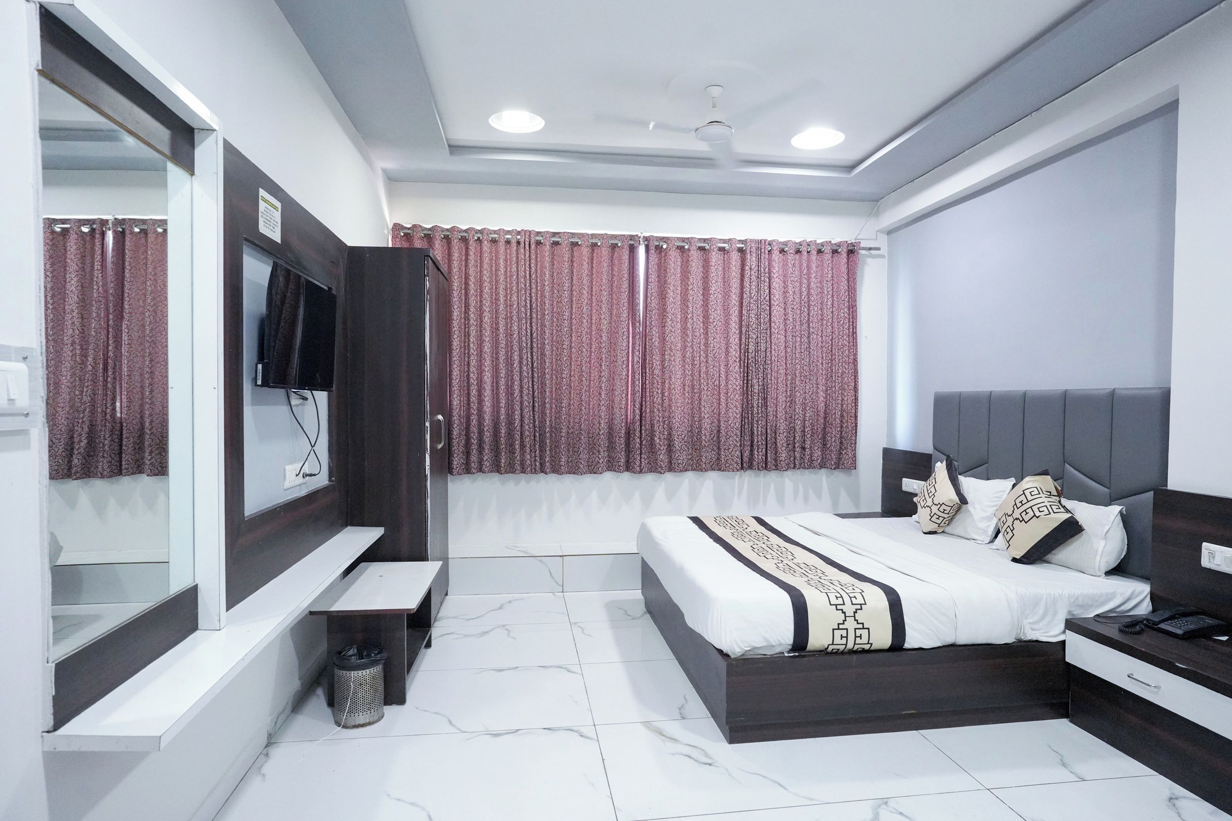 Un dormitorio moderno con cama, mesita de noche y un espejo grande.