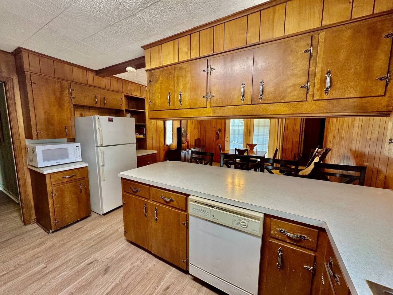 A kitchen with wooden cabinets, a microwave, a refrigerator, and a dishwasher.