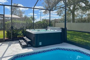A hot tub in a covered outdoor area with a pool. - Windsor Palms Escape | Private Pool & Game Room (Kissimmee)