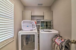 A laundry room with two stacked washers and dryers, a drying rack, and a stroller with a child's seat. - Windsor Palms Escape | Private Pool & Game Room (Kissimmee)