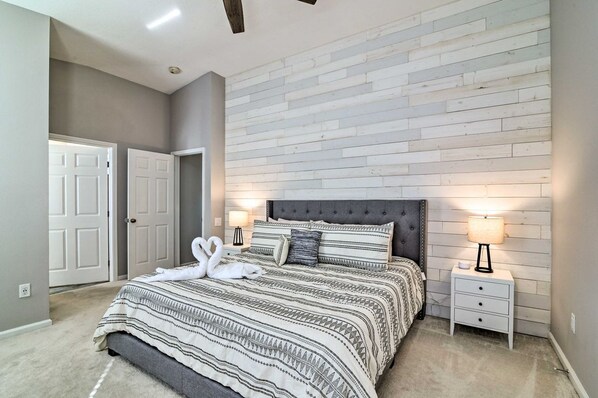 Een slaapkamer met een bed, twee nachtkastjes, een hoofdbord en een wand met een houten paneeldecor.