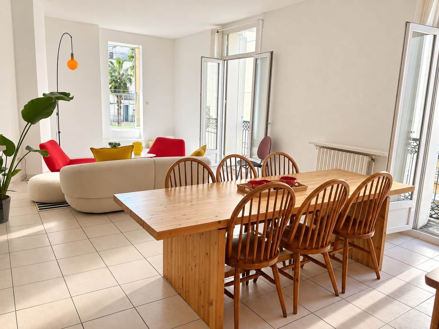 Un coin repas avec une table et des chaises en bois, un canapé avec des coussins et une plante en pot.