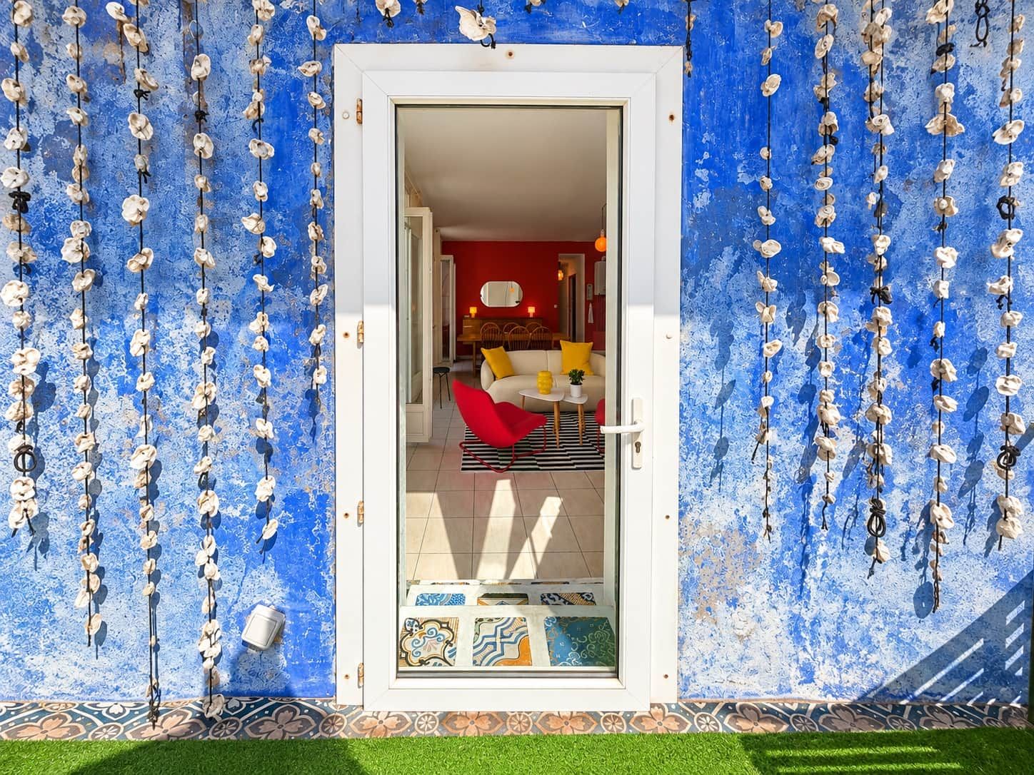 Ovi, jonka kautta pääsee huoneeseen, jossa on punainen seinä, valkoinen ovi ja kuvioitu lattia.