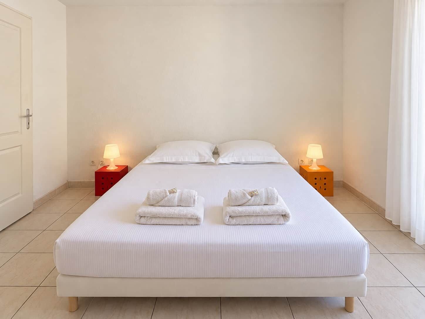 A single-bed room with a white bed, two bedside tables, and two lamps.