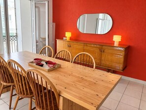 A dining area with a wooden table, chairs, a cabinet with a mirror, and a tray with bowls. - "Le Corail" – Stunning 2-bedroom apartment in the city center (Sète)