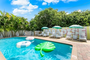 A swimming pool with inflatable toys, lounge chairs, and umbrellas. - Luxury Resort - Pool · GolfSim · GameRoom· FirePit· Hot Tub (Seminole)