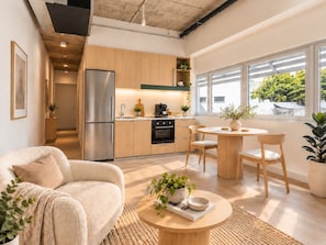 A modern kitchen with wooden cabinets, a stainless steel refrigerator, and a dining area with a round table and chairs. - Family Friendly 2-bed Apartment Darwin City (Darwin)