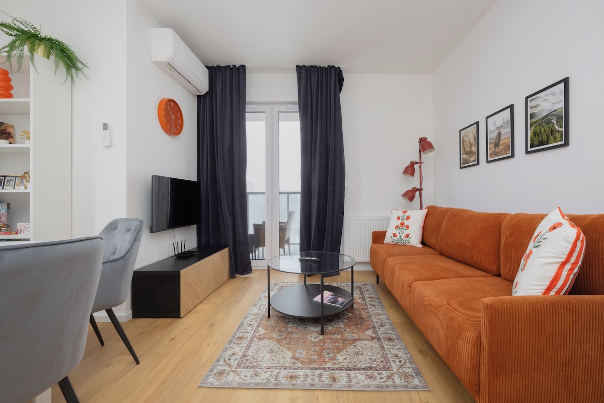 Uma sala de estar moderna com um sofá, TV e uma mesa de centro de vidro.