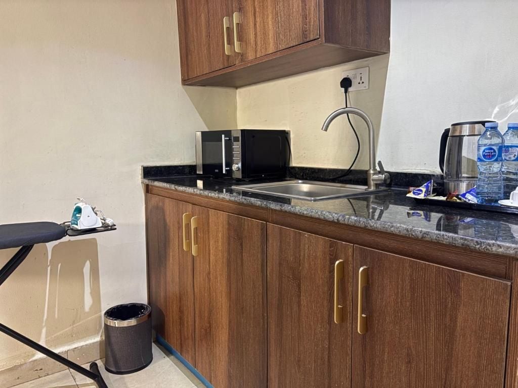 A compact kitchenette with a microwave, toaster, sink, and a coffee maker.