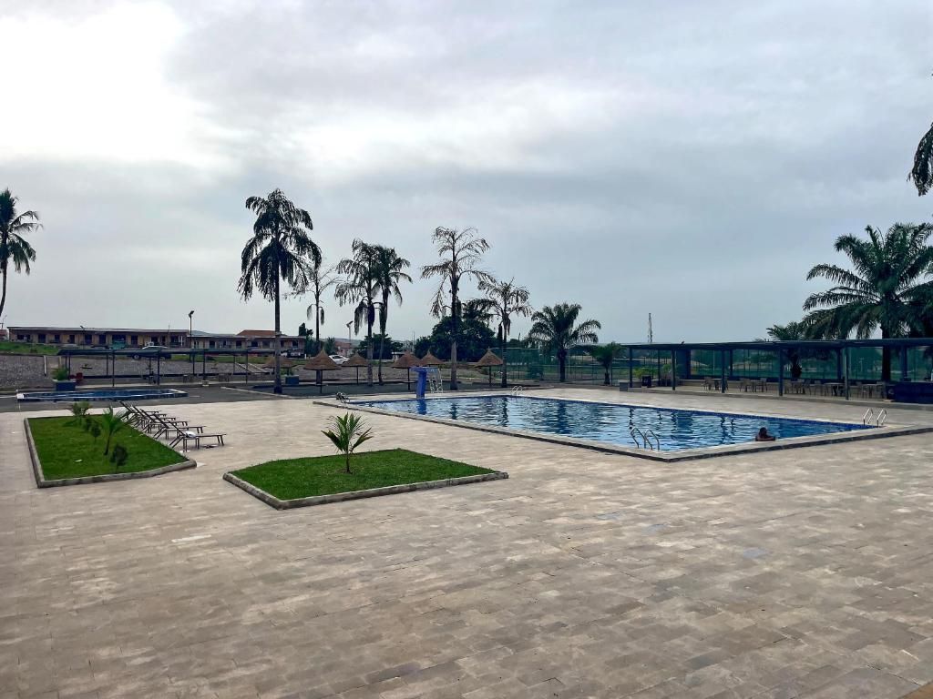 Zona de piscina con palmeras y un área de descanso cubierta.