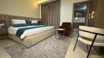 Ein Hotelzimmer mit einem großen Bett, einem Sessel, einem Schreibtisch und einem Kleiderschrank.