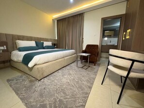 Habitación de hotel con una cama grande, una silla, un escritorio y un armario.