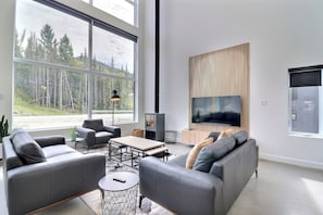 Ein modernes Wohnzimmer mit Kamin, Sofa, Couchtisch und einem an der Wand montierten Fernseher.