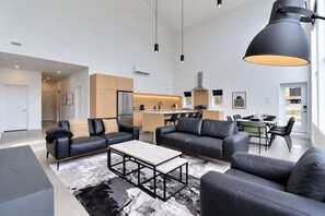 Ein modernes Wohnzimmer mit einer Sofagarnitur, einem Couchtisch und einem Essbereich mit Stühlen.