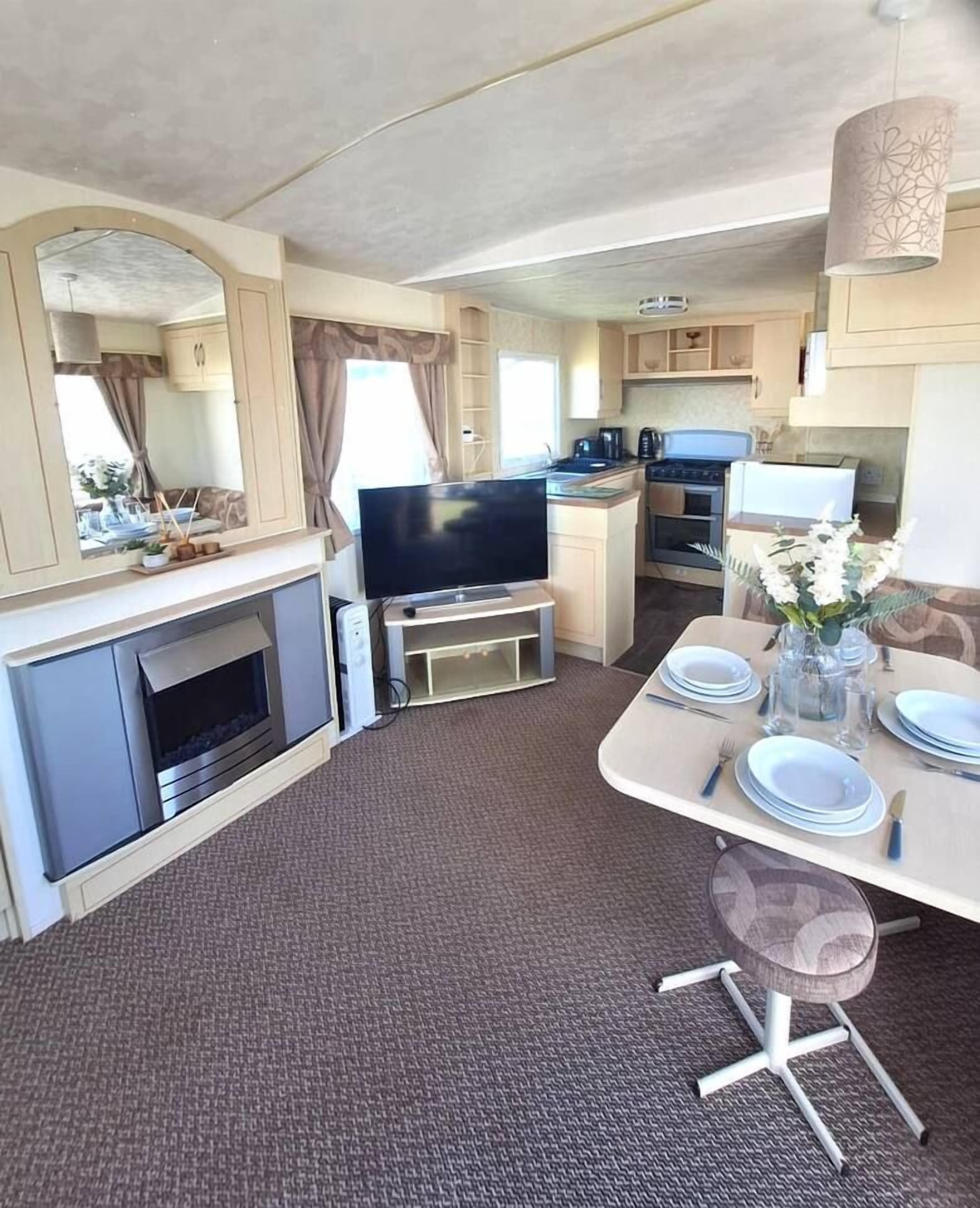 A compact living space with a dining area, kitchenette, and a fireplace.