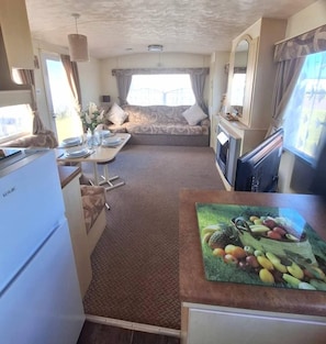 Ein kompaktes Wohnmobil-Interieur mit Küchenzeile, Essbereich und Schlafgelegenheit.