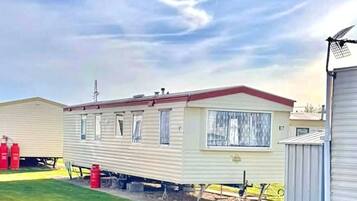 Une maison mobile avec un toit rouge, une fenêtre et un petit garage attenant.