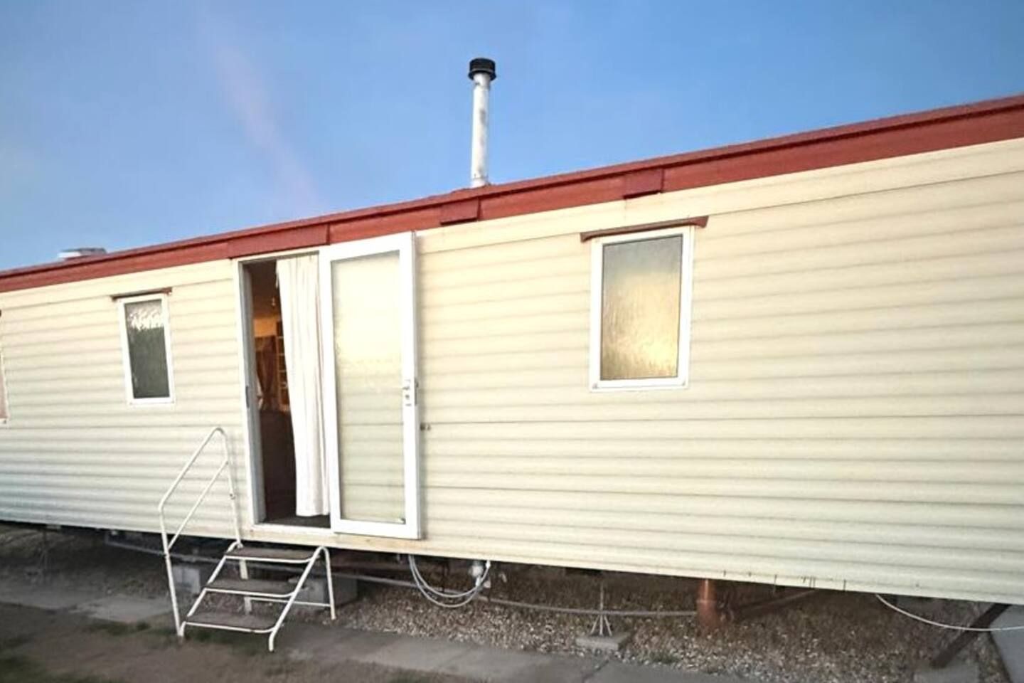 A mobile home with a red roof, a sliding door, and a small window.