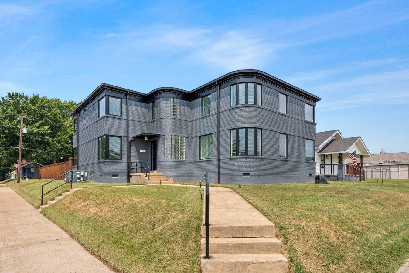 A modern two-story house with a curved facade, large windows, and a front porch.