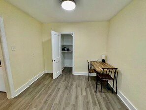 A room with a dining table and chairs, a white door leading to a closet, and a light fixture on the ceiling. - 1br apartment in NLR (North Little Rock)