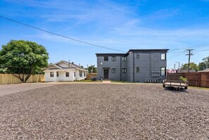 A residential area with a modern two-story house, a gravel driveway, and a wooden fence. - 1br apartment in NLR (North Little Rock)