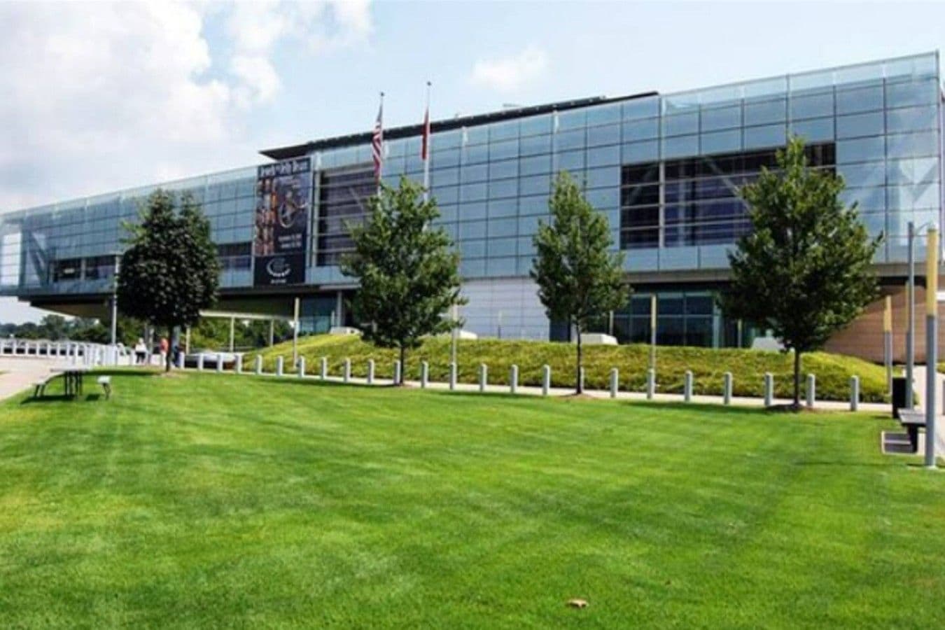 A modern building with a glass facade, a well-maintained lawn, and a few trees.